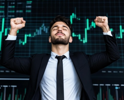 A confident businessman celebrating with a trophy while standing in front of a large screen displaying stock market charts