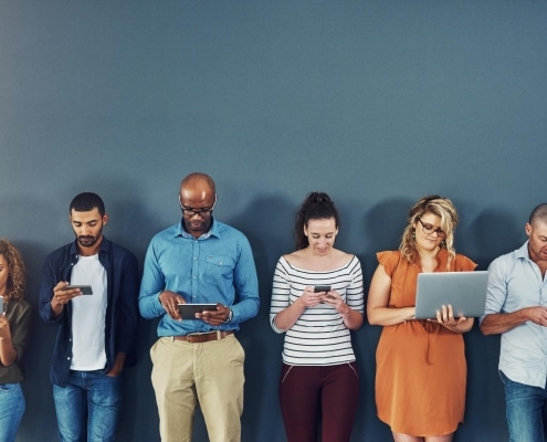 A group of people distracted due to the overuse of technology against gray studio background