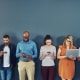 A group of people distracted due to the overuse of technology against gray studio background