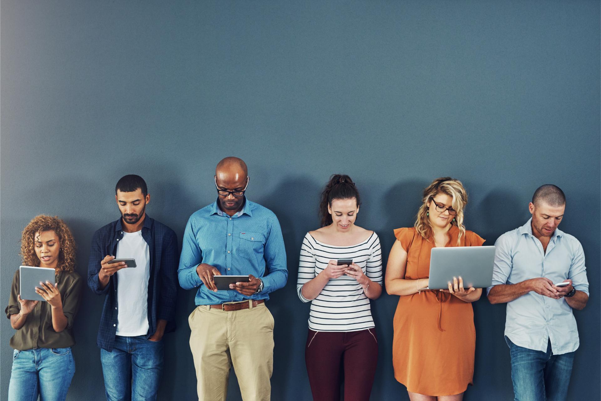 A group of people distracted due to the overuse of technology against gray studio background