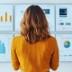 A woman with curly hair observes multiple data analysis screens showcasing various graphs and charts enhanced ()