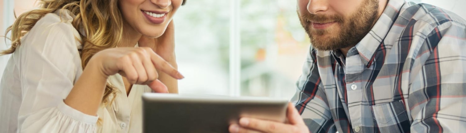 Close up portrait of happy young couple using a digital tablet together at a coffee shop