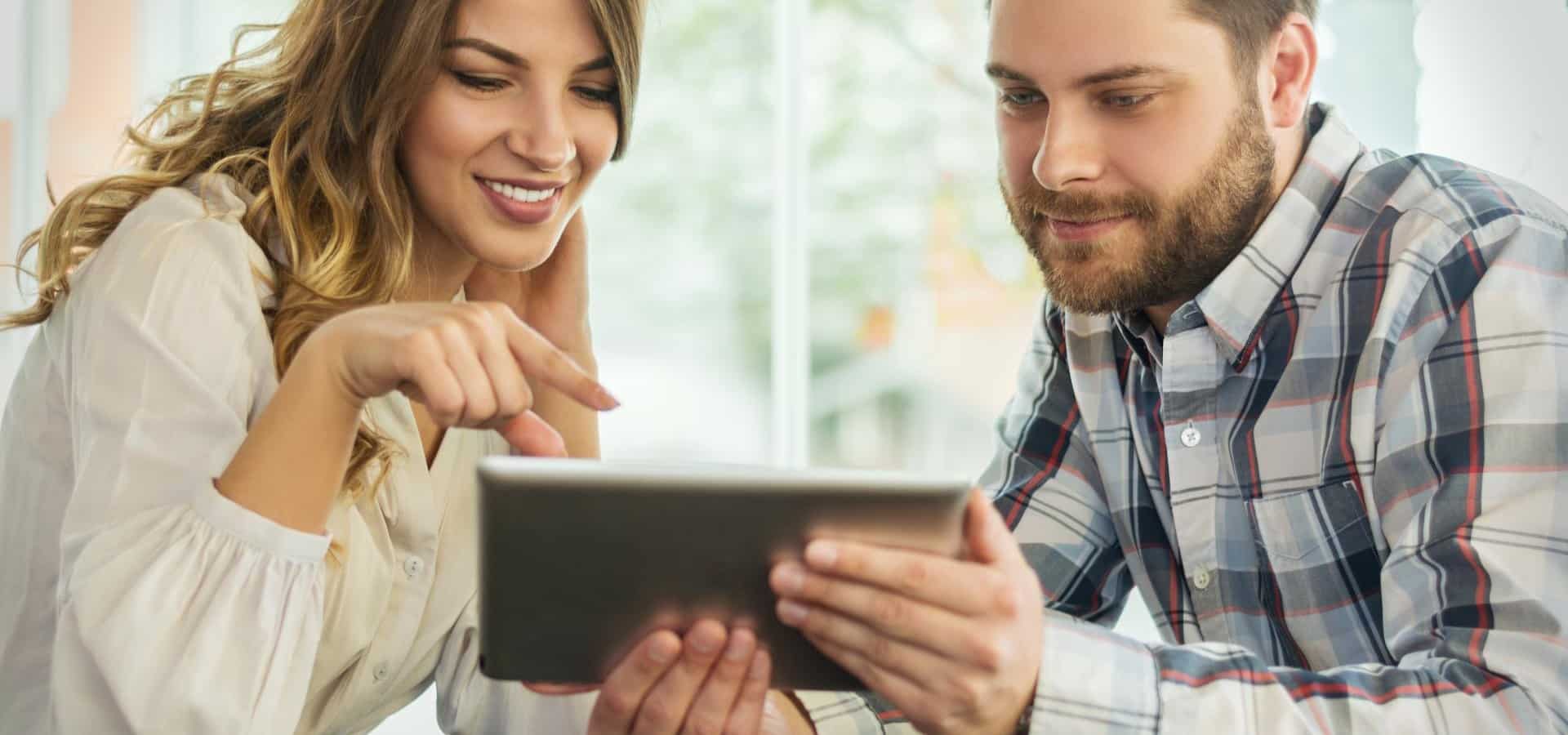 Close up portrait of happy young couple using a digital tablet together at a coffee shop