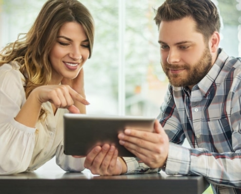 Close up portrait of happy young couple using a digital tablet together at a coffee shop