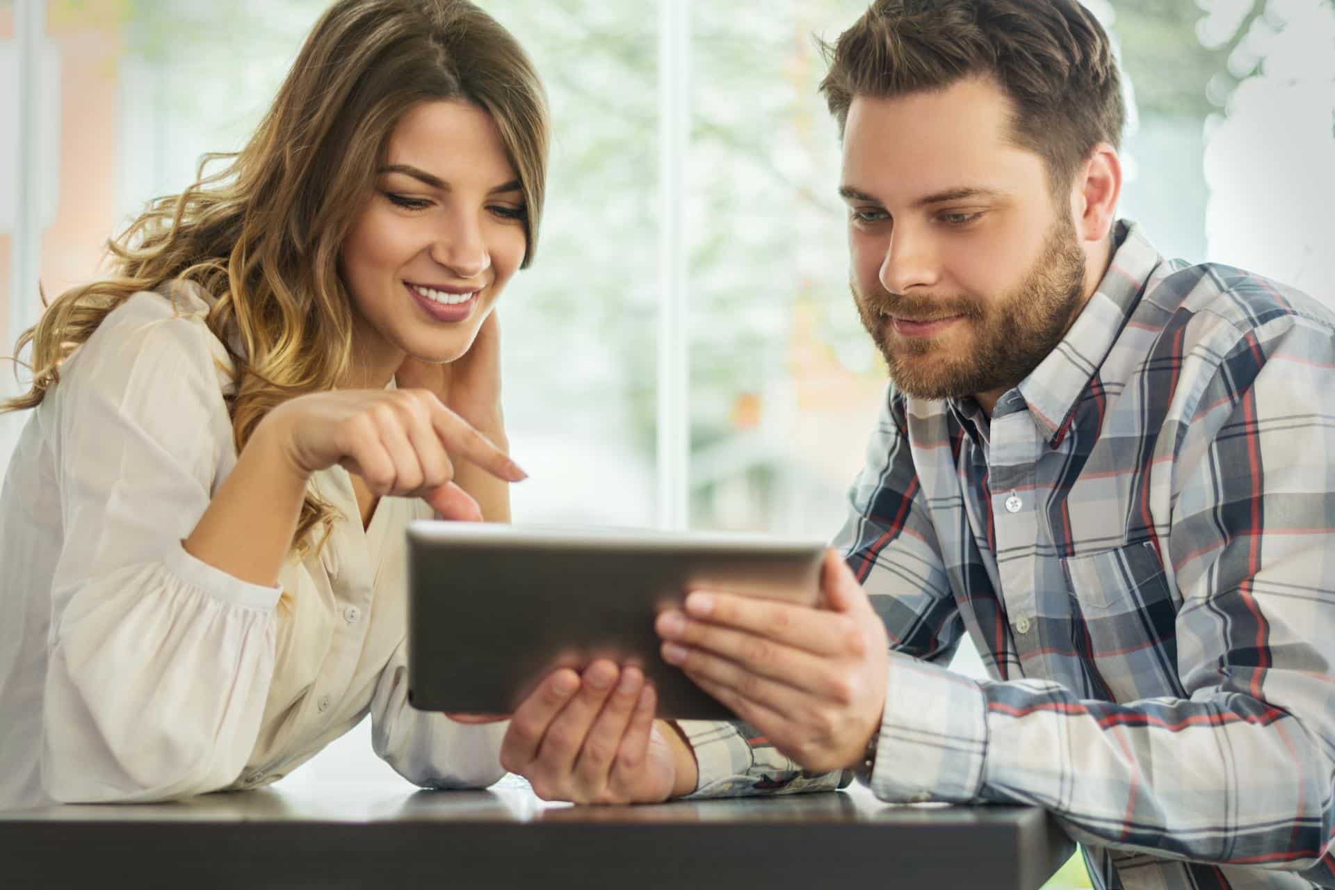 Close up portrait of happy young couple using a digital tablet together at a coffee shop
