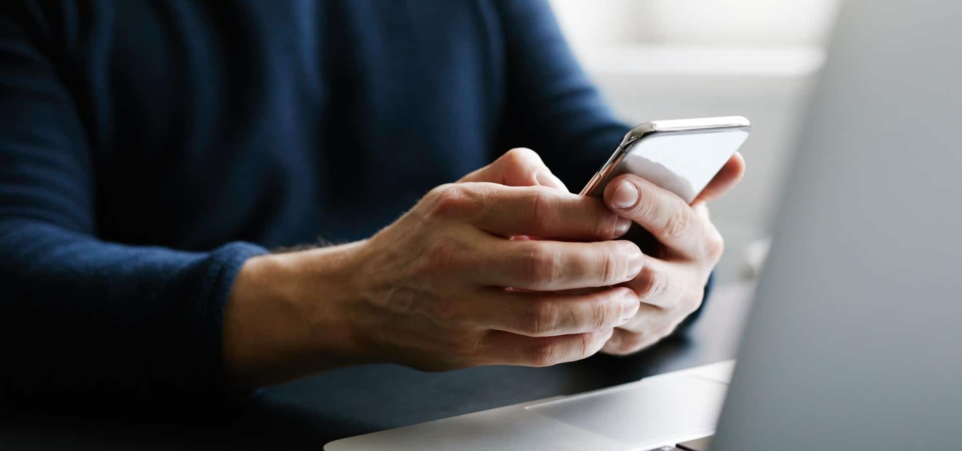 Man with mobile phone and laptop in office