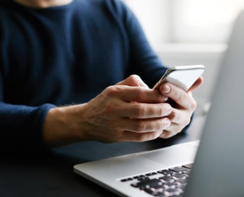 Man with mobile phone and laptop in office